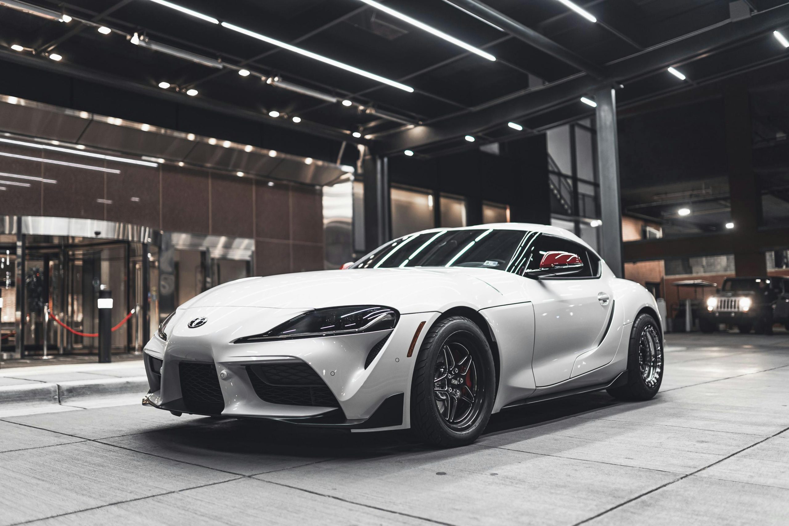 A white sports car displayed indoors, showcasing its design and luxury appeal.